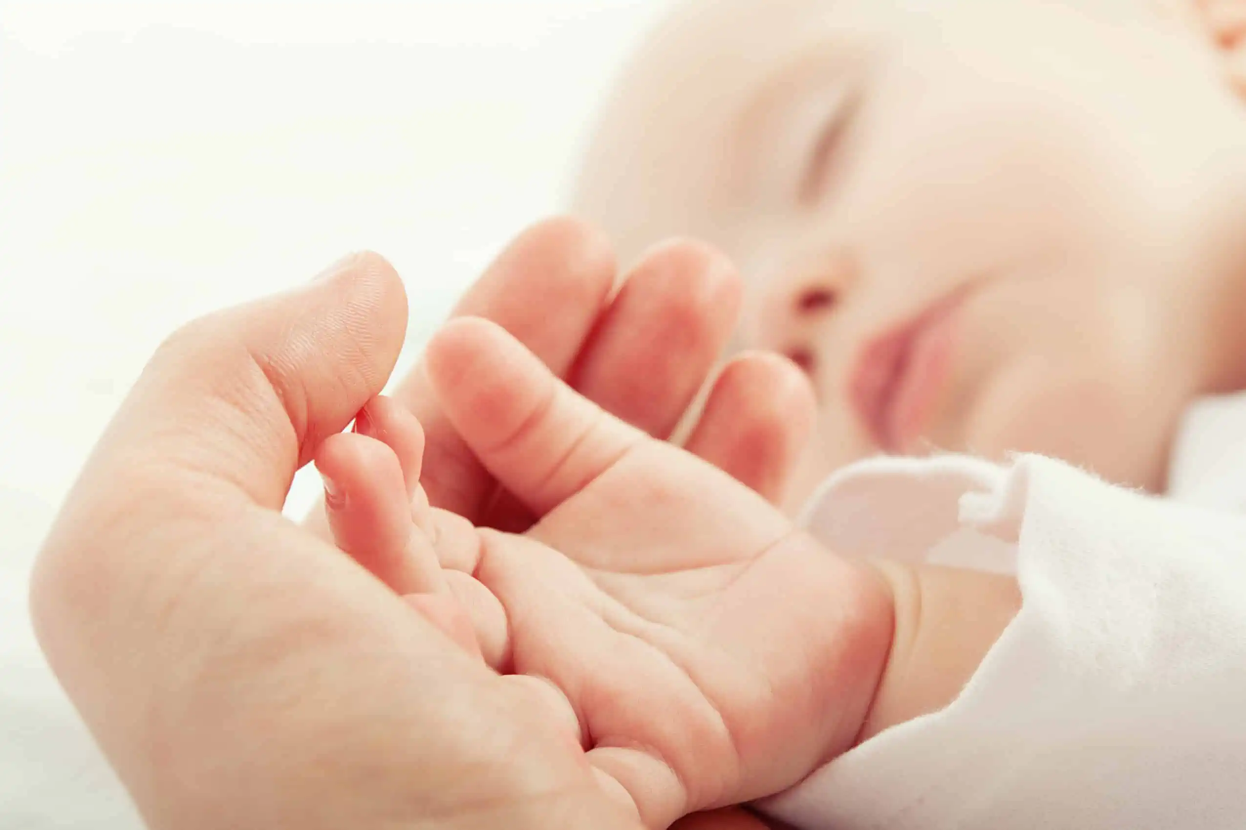 Parent holding sleeping babys hand